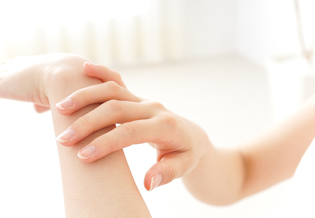 腕を触って肌触りを確認する女性