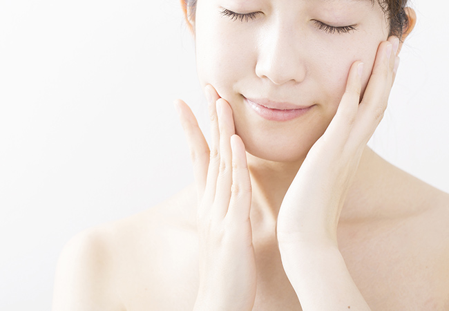 目を閉じ頬に手を当てる女性