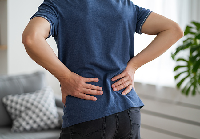 腰痛のため腰に手を当てる男性