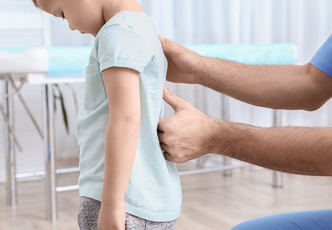 医師から子どもの背骨の検査うける子ども